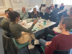 Photograph of workshop attendees seated around a table and having a discussion.